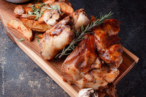 A set dish: a large fried piece of meat on the bone, country-style grilled potatoes, a mini salad of cabbage, bean sprouts, chia seeds and green onions. Original serving on a wooden cutting board. photo