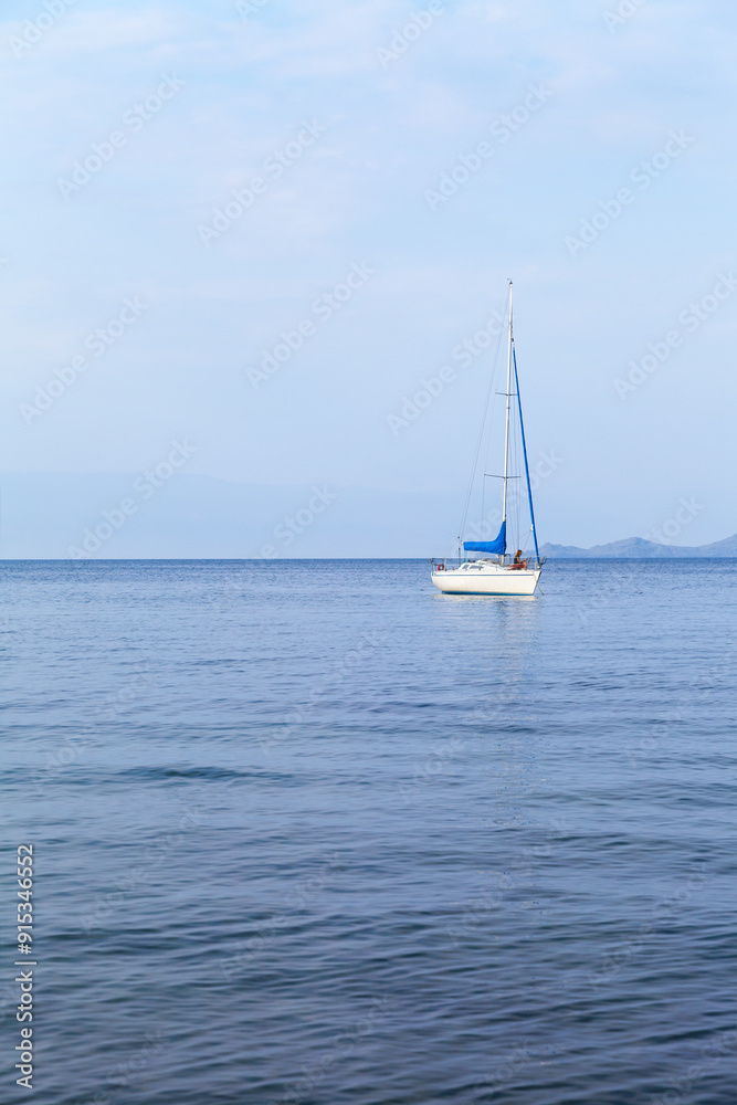Summer vacation on Baikal Lake. A tourist girl is relaxing on a pleasure sailing yacht and taking pictures of a beautiful seascape with Olkhon Island in the distance on her mobile phone Summer vacation on Baikal Lake. A tourist girl is relaxing on a pleasure sailing yacht and taking pictures of a beautiful seascape with Olkhon Island in the distance on her mobile phone