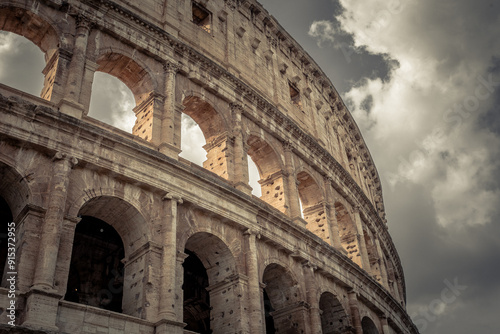 Left side of frame Roman Colosseum with clouds in sky on warm day
