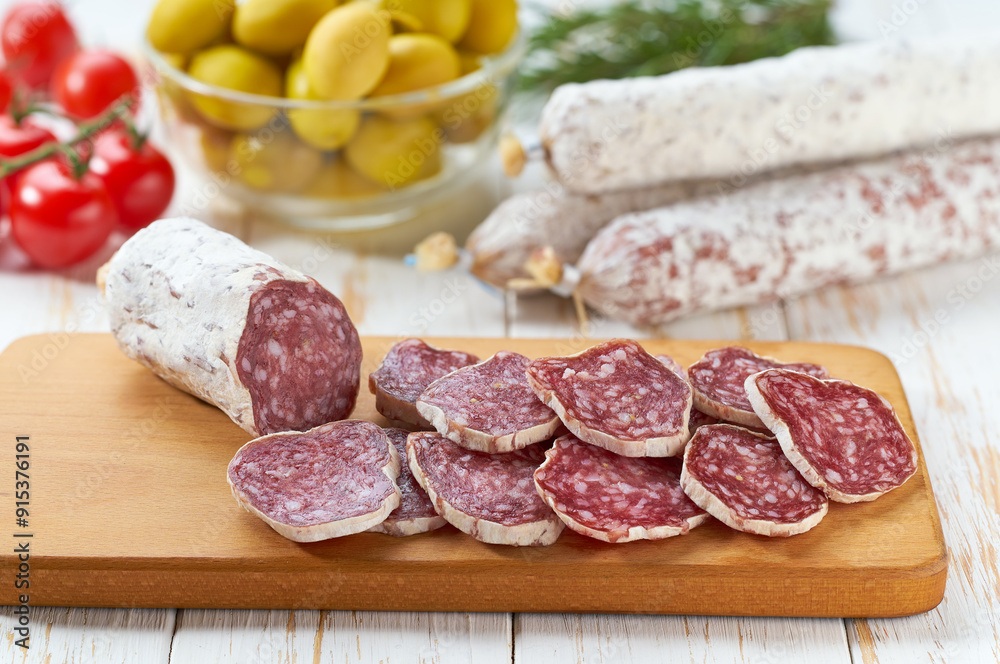 traditional Spanish salami fuet sausage or dry sausage cut in slices in a kitchen table. traditional Spanish salami fuet sausage or dry sausage cut in slices in a kitchen table.