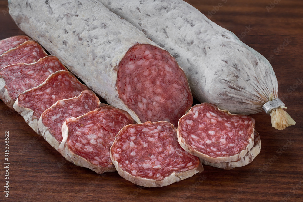 Slices of delicious spanish sausage fuet on a wooden table, selective focus. Slices of delicious spanish sausage fuet on a wooden table, selective focus.