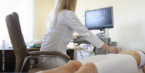 Obraz na płótnie Woman doctor makes an ultrasound of the abdomen of a woman, rear view. Clinical consultation and diagnosis of diseases w salonie