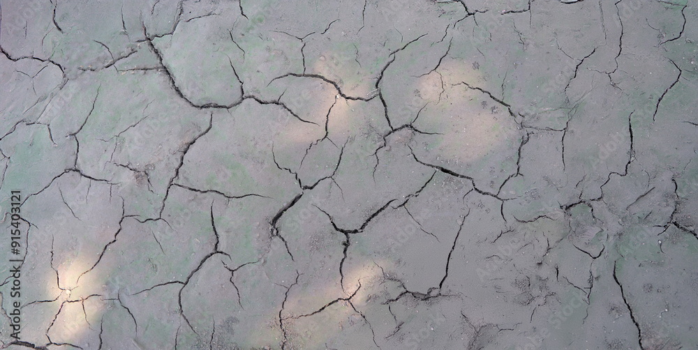 Sun beams on dry cracked gray ground, close-up. Soil erosion, drought, poor ecology, lack of rainfall Sun beams on dry cracked gray ground, close-up. Soil erosion, drought, poor ecology, lack of rainfall