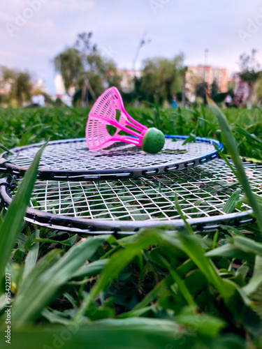 Closeup side view of two badminton rackets and shuttlecock on green grass