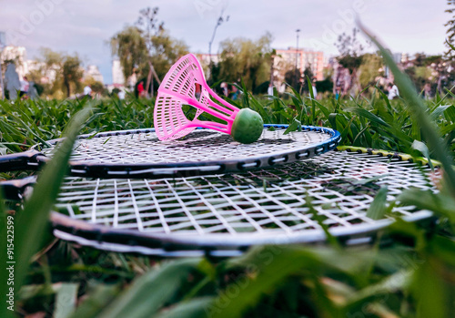 Closeup side view of two badminton rackets and shuttlecock on green grass