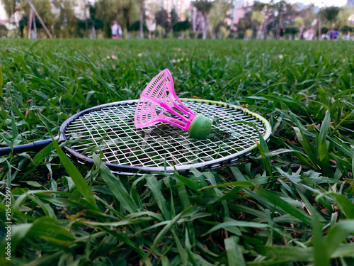 Closeup side view of badminton racket and shuttlecock on green grass