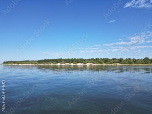 Island on a lake with white sand on a sunny day.