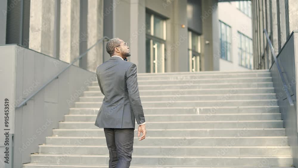 African American businessman walking up stairs in outdoor urban setting, engaged in phone conversation. Captures professional demeanor, purposeful movement, and modern lifestyle. Rear back view African American businessman walking up stairs in outdoor urban setting, engaged in phone conversation. Captures professional demeanor, purposeful movement, and modern lifestyle. Rear back view