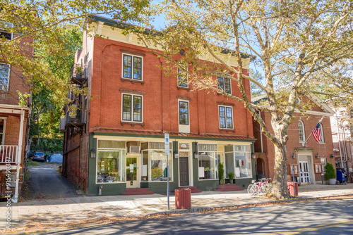 Traditional American brick buildings with shops on ground floor along a tree lined street in a historic downtown on a sunny autumn day