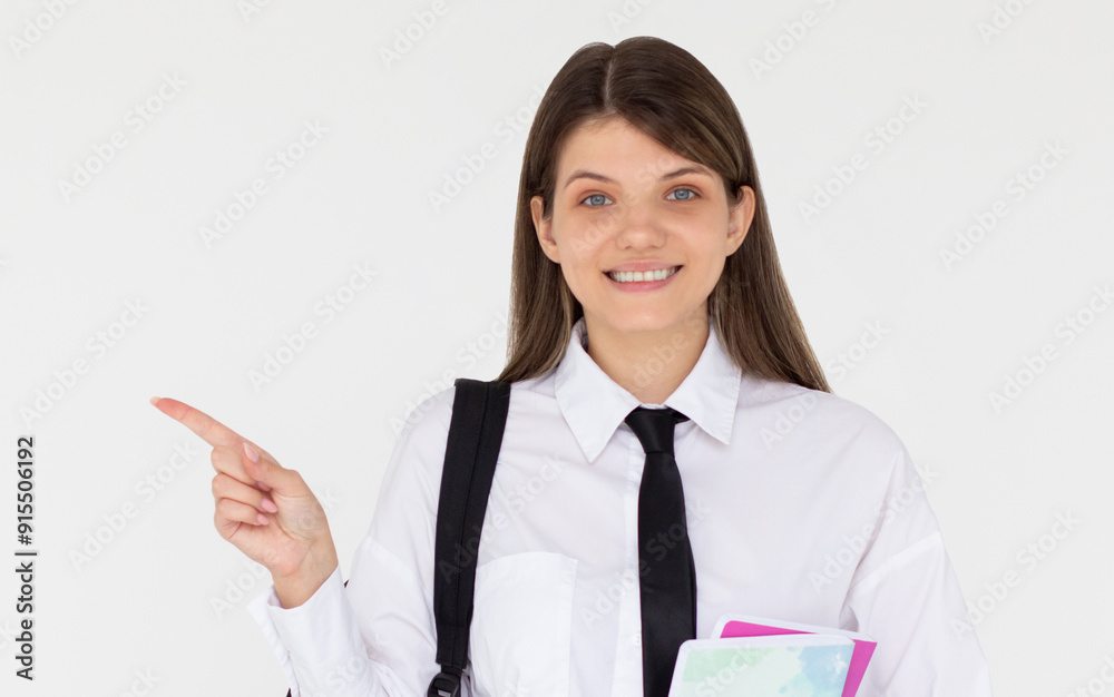 Hey look. Smiling pretty female model pointing fingers left at empty space and inviting to check it out, showing advertisement on white background. Girl with notepads in hands. Hey look. Smiling pretty female model pointing fingers left at empty space and inviting to check it out, showing advertisement on white background. Girl with notepads in hands.