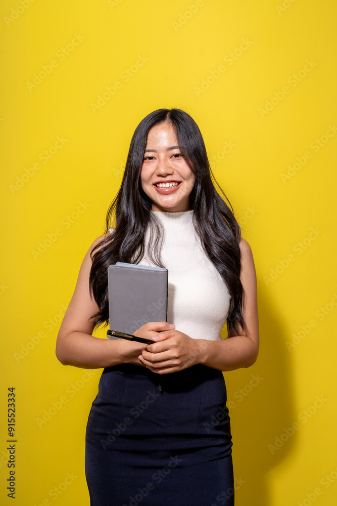 A woman is smiling and holding a book
