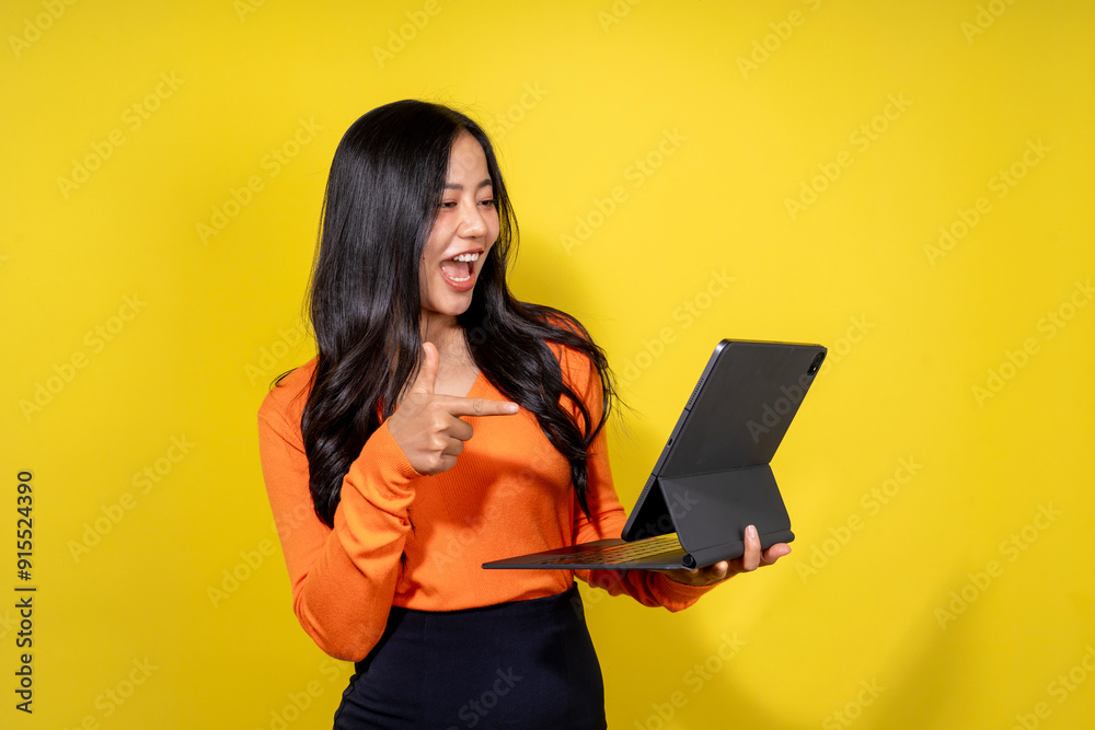 A woman in an orange shirt is holding a tablet