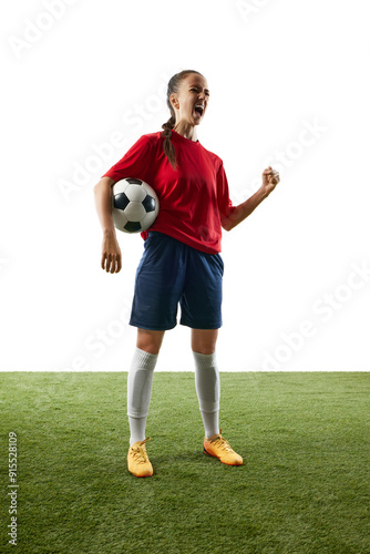 Full-length photo of young, female football athlete celebrates game-changing moment standing on stadium with ball and shouting of joy. Concept of women and sport, team games, victory, action. Ad photo