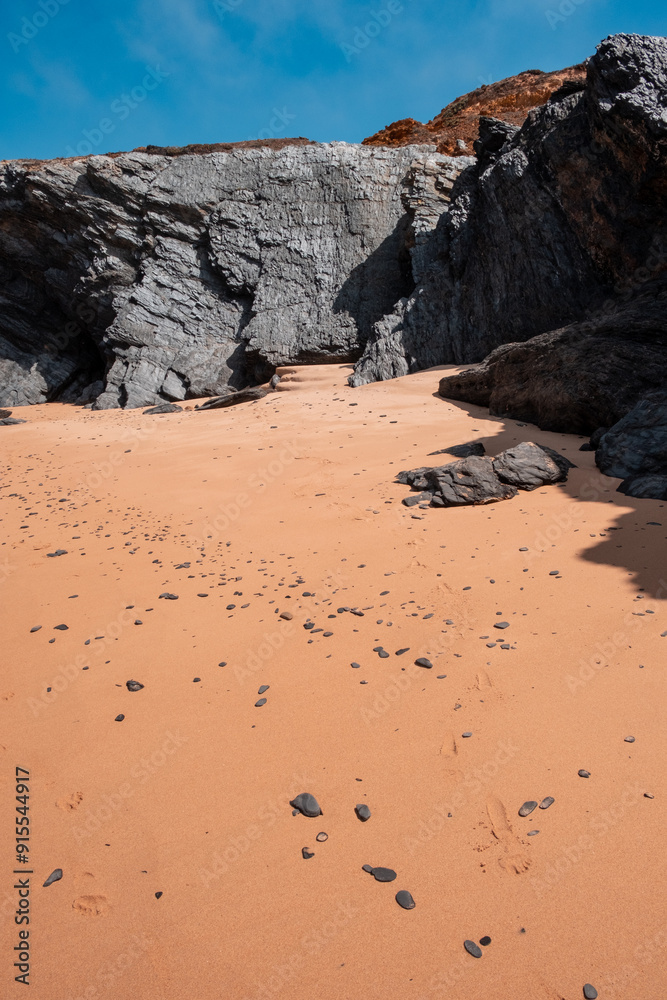 A tranquil beach scene, a rocky outcrop, and the soft sand, capturing the serene beauty of coastal nature.