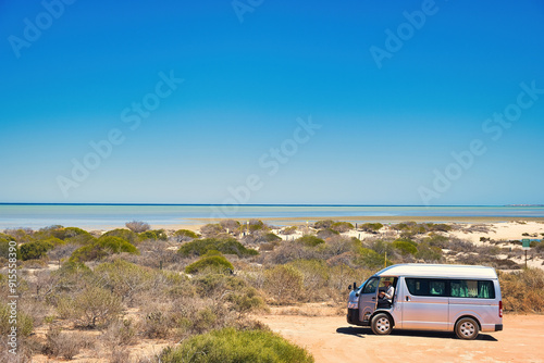 Small campervan with elderly woman in the dunes close to Denham, Western Australia. In the distance the tropical waters of Shark Bay, Coral Coast
 photo