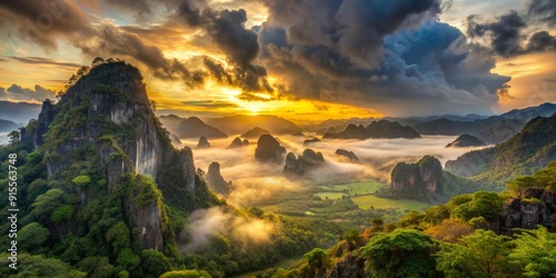 Soft yellow light illuminates rugged mountains and valleys beneath a vast gray altostratus cloud sheet at Khao Chang Hai Cave, Na Yong District, Trang Province, Thailand.