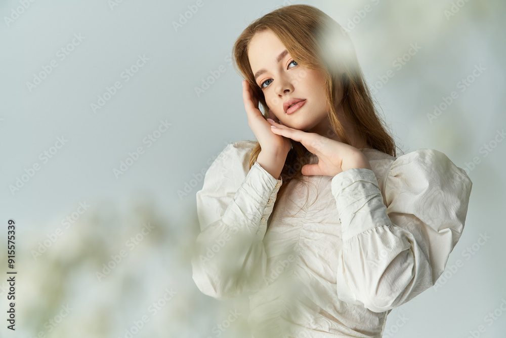 A young woman gently poses among soft blossoms, radiating beauty and grace.