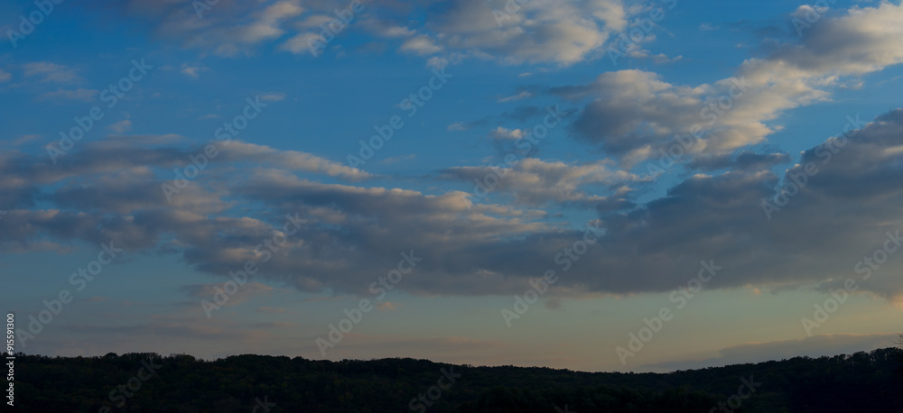 Fototapeta premium Clouds in the evening sky against the backdrop of dark silhouettes of hills.
