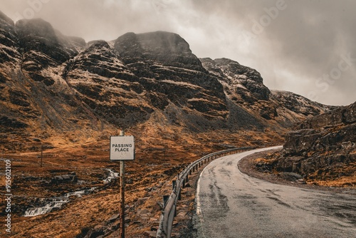 Scenic view of a mountain road with a 'Passing Place' sign under a cloudy sky