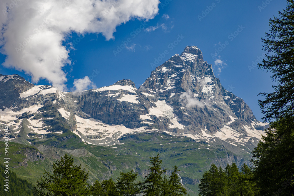 view of the matterhorn from the aosta valley in summer with a sunny blue sky and some clouds view of the matterhorn from the aosta valley in summer with a sunny blue sky and some clouds