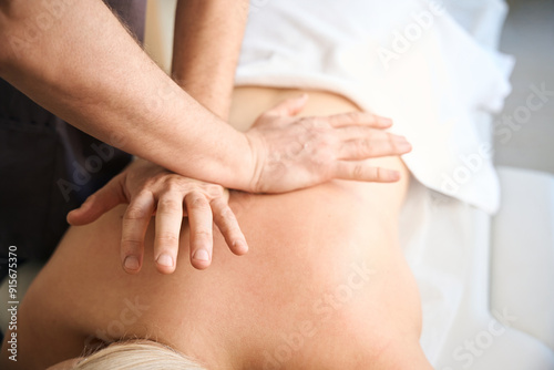 Massotherapist performing cross-hand myofascial release on patient mid back