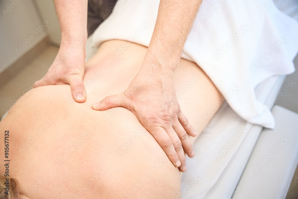 Adult patient receiving mid-back massage performed by masseur Adult patient receiving mid-back massage performed by masseur