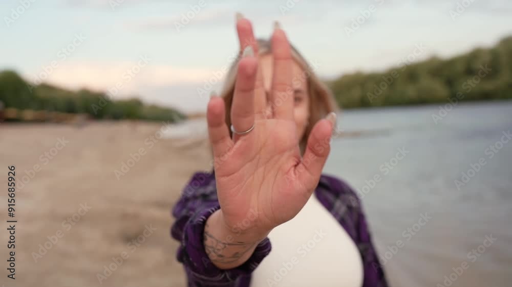 Beautiful young girl with short hair in purple shirt on river bank looking at camera, smiling and adjusting hair. Walk on beach against sunset background in summer in nature Beautiful young girl with short hair in purple shirt on river bank looking at camera, smiling and adjusting hair. Walk on beach against sunset background in summer in nature