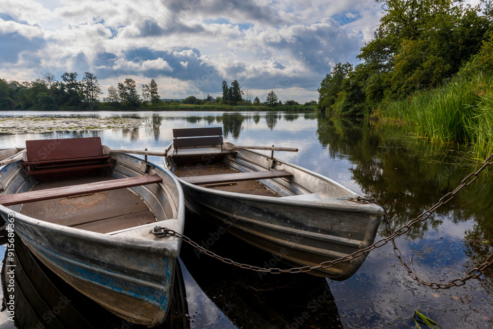 Aufnahme von zwei älteren Ruderbooten auf einem See am Ufer festgekettet. Aufnahme von zwei älteren Ruderbooten auf einem See am Ufer festgekettet.