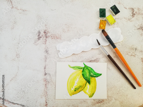 Watercolor lemon drawing, brushes and paints on clear table. Free space for text