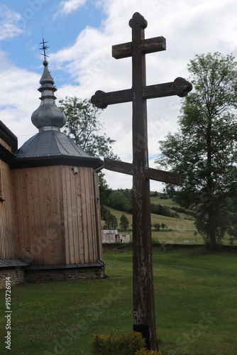 wooden Orthodox cross next to the wooden Orthodox church of St. Michael the Archangel in Turzansk in the Bieszczady Mountains in Poland photo