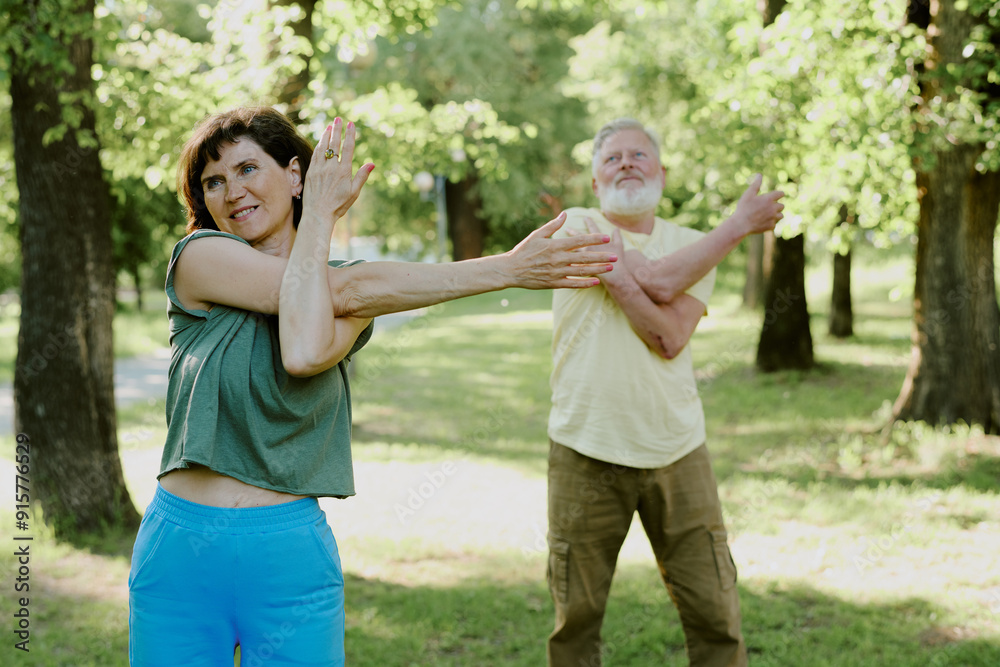 Senior Caucasian partners crossing their arms to make them more flexible during yoga practice Senior Caucasian partners crossing their arms to make them more flexible during yoga practice