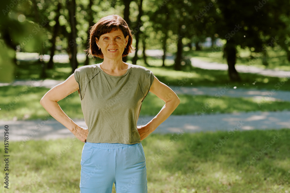 Portrait of smiling brunette woman dressed in cotton sportswear looking directly at camera while having open air workout Portrait of smiling brunette woman dressed in cotton sportswear looking directly at camera while having open air workout