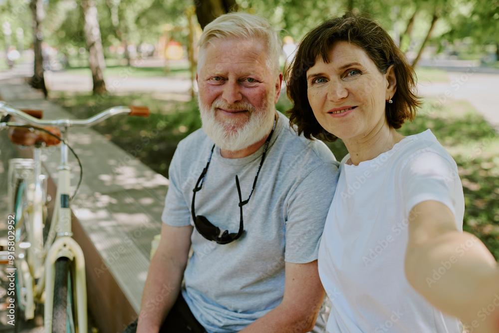Obraz premium Senior brunette woman taking selfie with her beloved silver-haired husband while they having walk