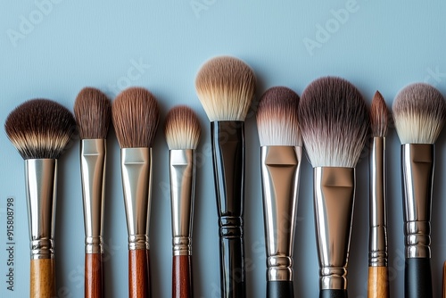 A Collection of Professional Makeup Brushes Arranged Neatly on a Light Blue Surface