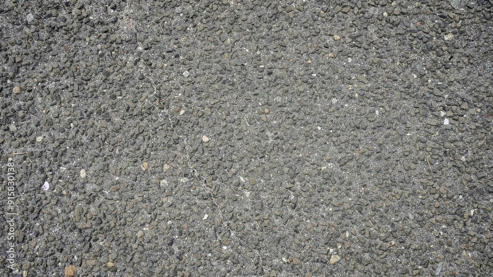 A close-up view of textured asphalt showing various stones during daylight hours A close-up view of textured asphalt showing various stones during daylight hours