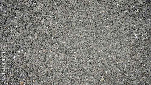 A close-up view of textured asphalt showing various stones during daylight hours