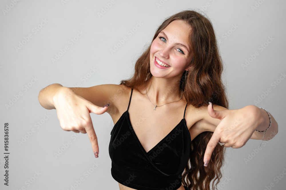 Smiling Woman Pointing Downwards In Studio Setting Smiling Woman Pointing Downwards In Studio Setting