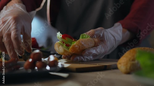 Yellow. Hot dogger uses professional skills carefully preparing hot dog at street food stand. General view of camera European specialist prepares hot hot dog uses trendy recipes, bun photo