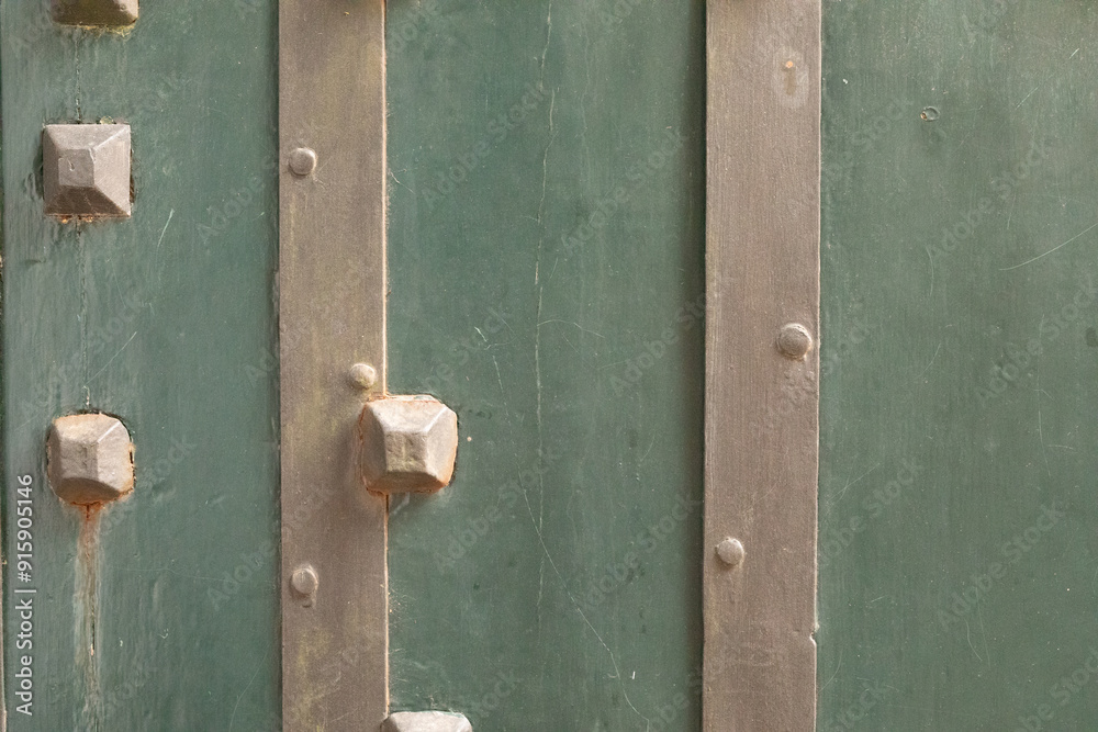 Close up of a weathered green door with metal accents Close up of a weathered green door with metal accents