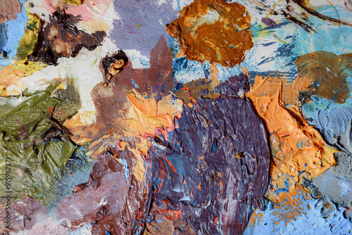 Colorful abstract texture. Smears of oil paint and a palette knife on an art palette. The concept of the modern school of art. Fragment of creative work. Colors of the year 2024