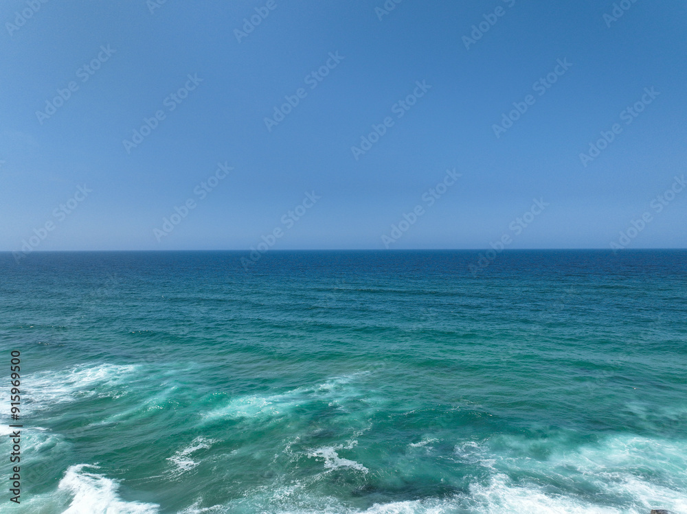 A vast expanse of turquoise ocean meets a cloudless blue sky A vast expanse of turquoise ocean meets a cloudless blue sky
