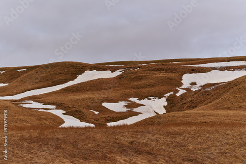 Patches of snow are slowly melting on the hillsides in early spring photo