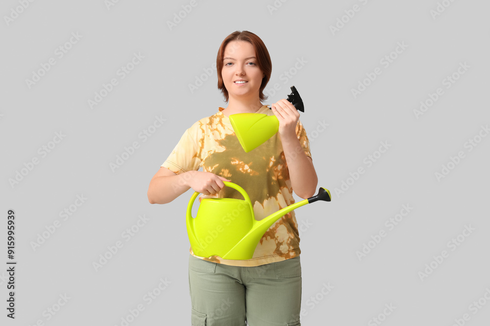 Smiling woman with watering can and spray bottle on grey background Smiling woman with watering can and spray bottle on grey background