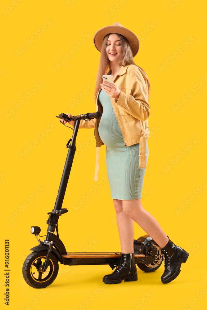 Beautiful young pregnant woman with electric kick scooter and mobile phone on yellow background Beautiful young pregnant woman with electric kick scooter and mobile phone on yellow background