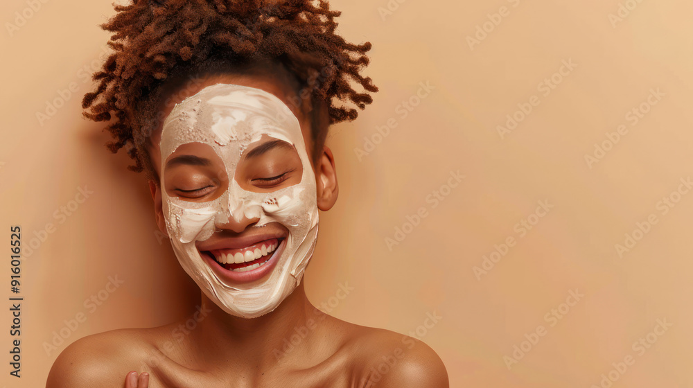 Young satisfied woman applying a face clay mask, smiling as she poses on a beige background, aiming for fresh and smooth skin Young satisfied woman applying a face clay mask, smiling as she poses on a beige background, aiming for fresh and smooth skin
