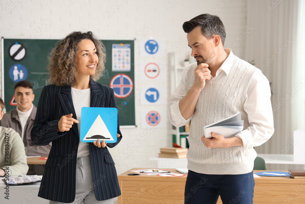 Fototapeta premium Female instructor with road sign and man at driving school