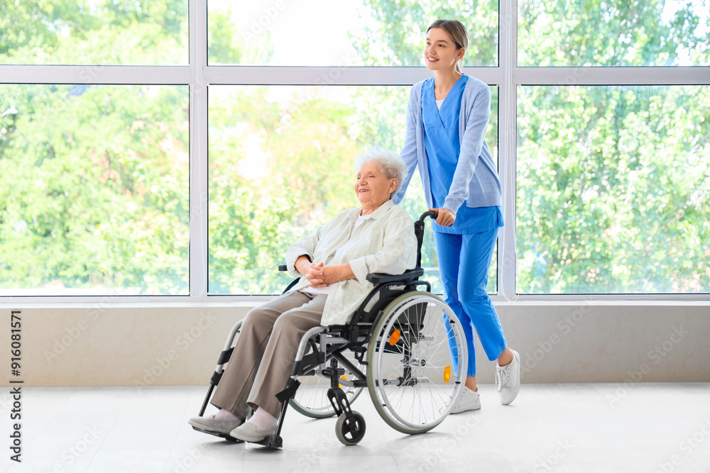 Senior woman in wheelchair with nurse near window at home Senior woman in wheelchair with nurse near window at home