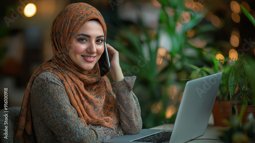 Smiling Muslim Woman in Hijab Working on Laptop and Talking on Phone for Modern Business and Technology Photography Themes photo