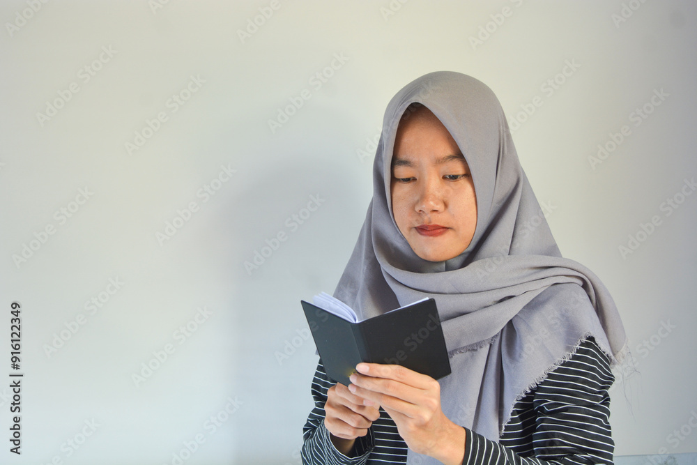 Portrait of joyful smiling positive woman with dark wavy hair standing holding paper notebook and showing empty paper, copy space. Indoor studio shot isolated on background. Portrait of joyful smiling positive woman with dark wavy hair standing holding paper notebook and showing empty paper, copy space. Indoor studio shot isolated on background.