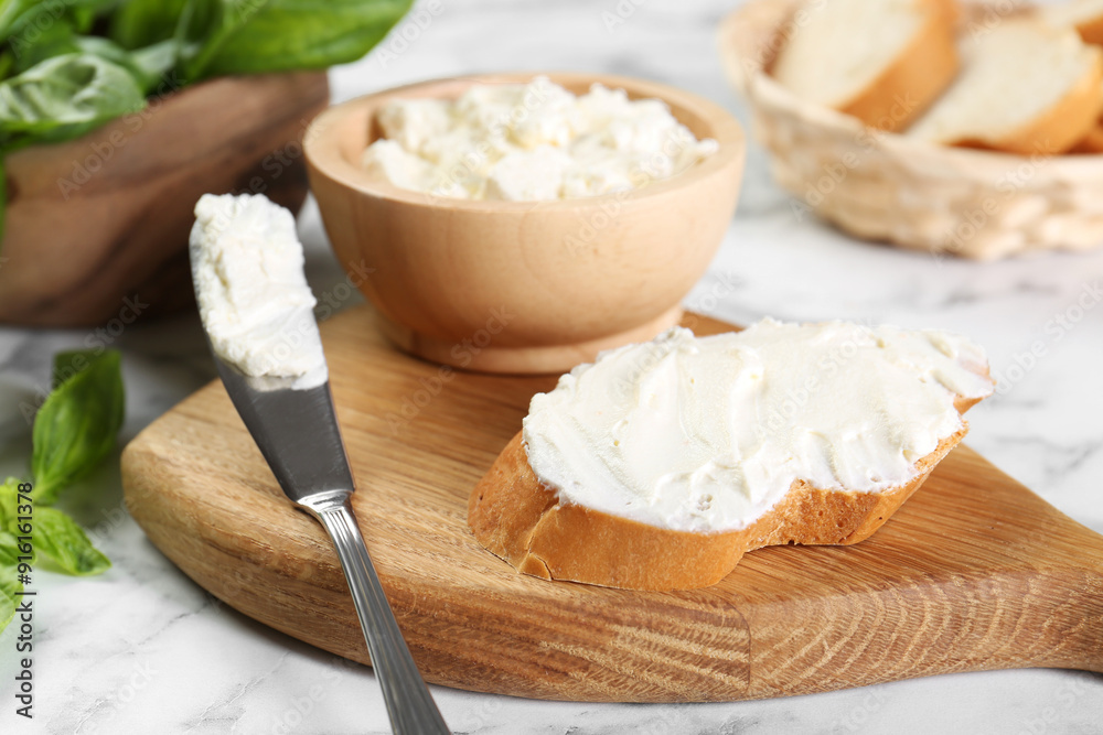 Piece of bread with cream cheese and knife on white marble table Piece of bread with cream cheese and knife on white marble table